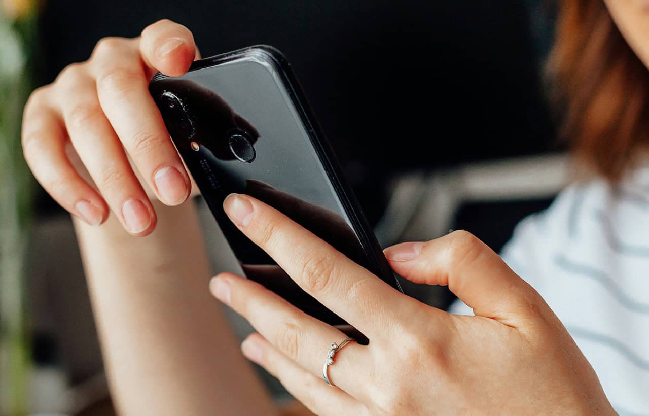 Close-up of person holding and using a smartphone for messaging or browsing.