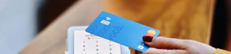 Close-up of a hand holding a blue stable card with a calculator in the background.
