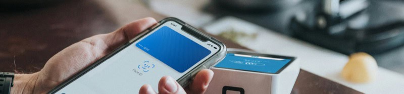 Close-up of a person using a mobile payment app on a smartphone at a card reader.